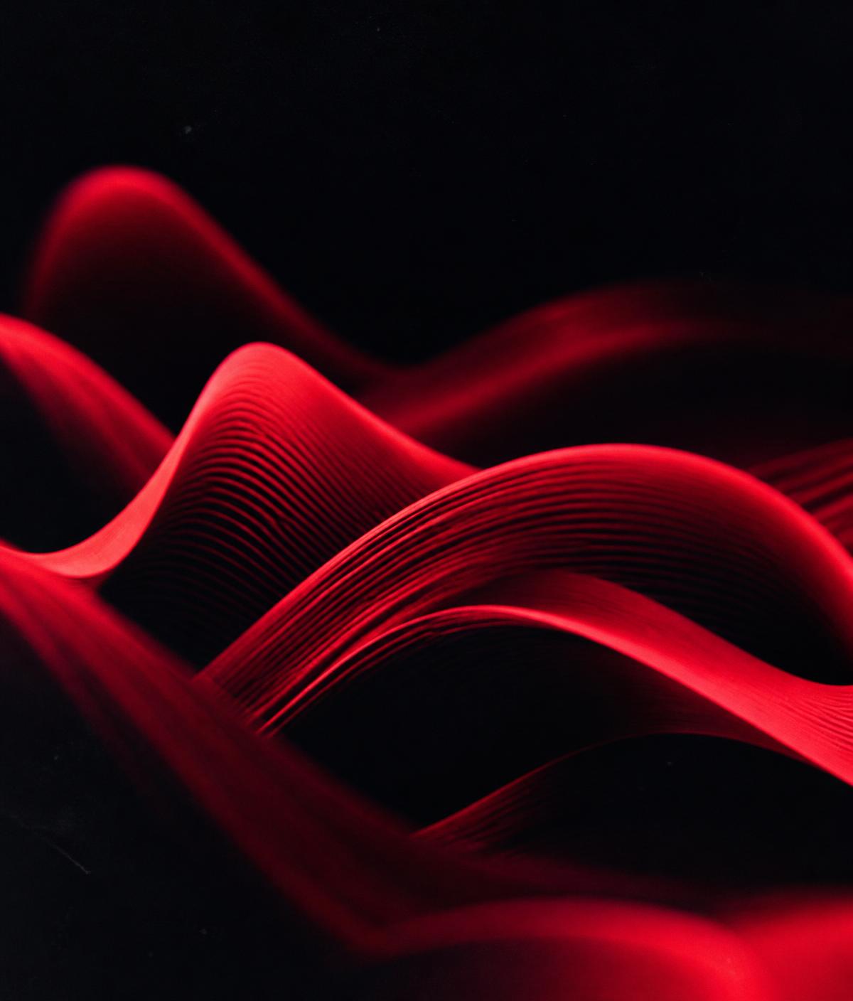 Sculptural red waveform ribbons flowing across a dark background